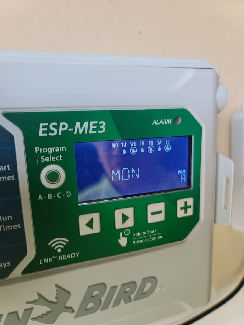 Irrigation controller display showing ESP-ME3 model with day settings and alarm feature.